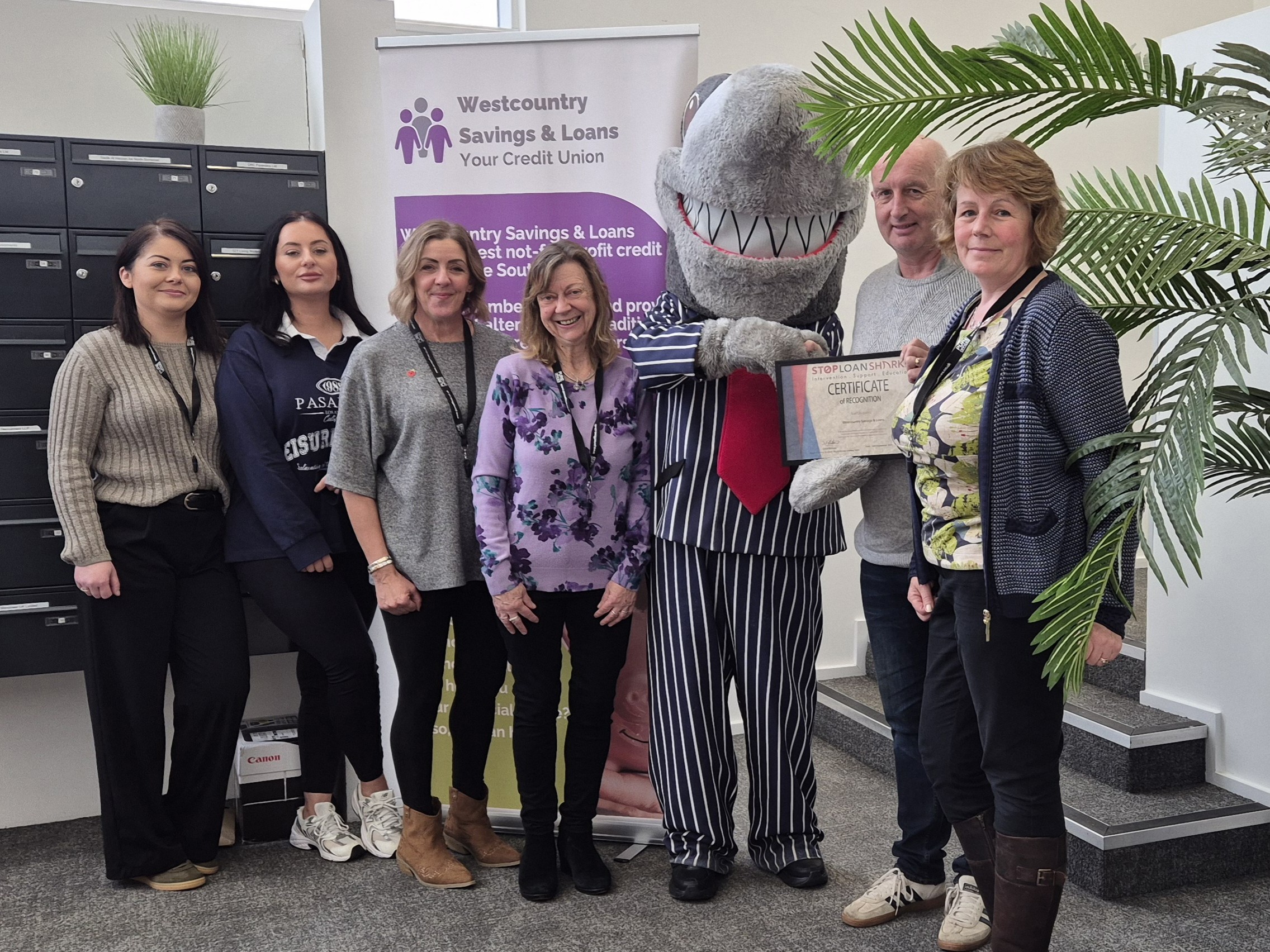 Westcountry Savings & Loans Credit Union team with the Stop Loan Sharks mascot during an office visit.